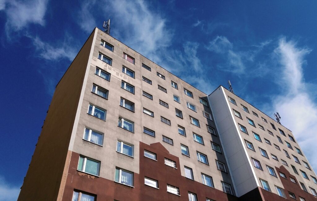 Low angle view of a modern urban apartment building with cloudy blue sky background.