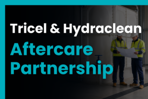 Two engineers reviewing plans beside a GRP water storage tank, representing the Tricel and Hydraclean aftercare partnership.